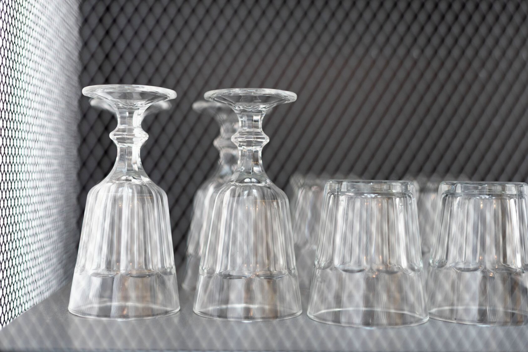 A row of clear glassware on a shelf with a textured background.