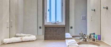 A modern bathroom with a large mirror, two sinks, and a window.