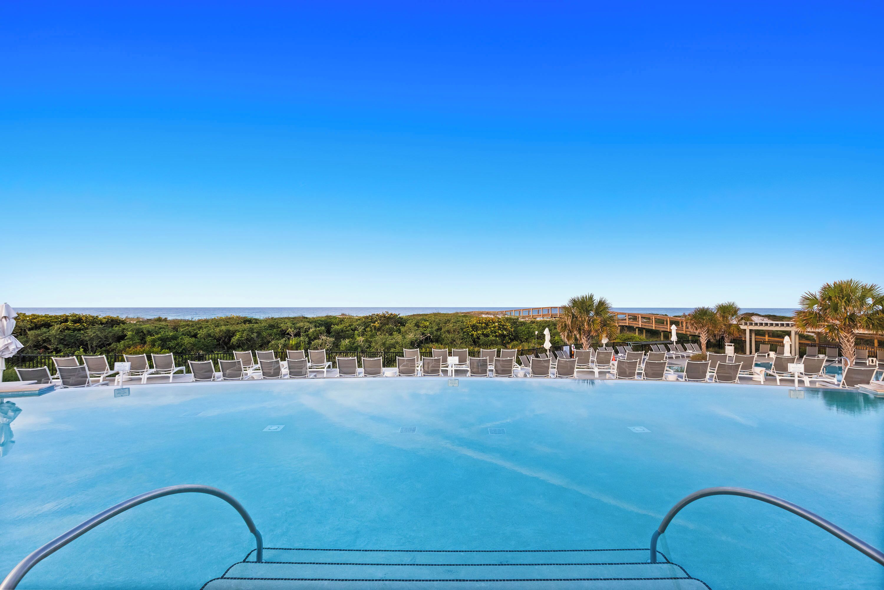 Une piscine à débordement avec des chaises longues et une vue sur l’océan.