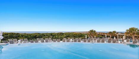 Une piscine à débordement avec des chaises longues et une vue sur l’océan.