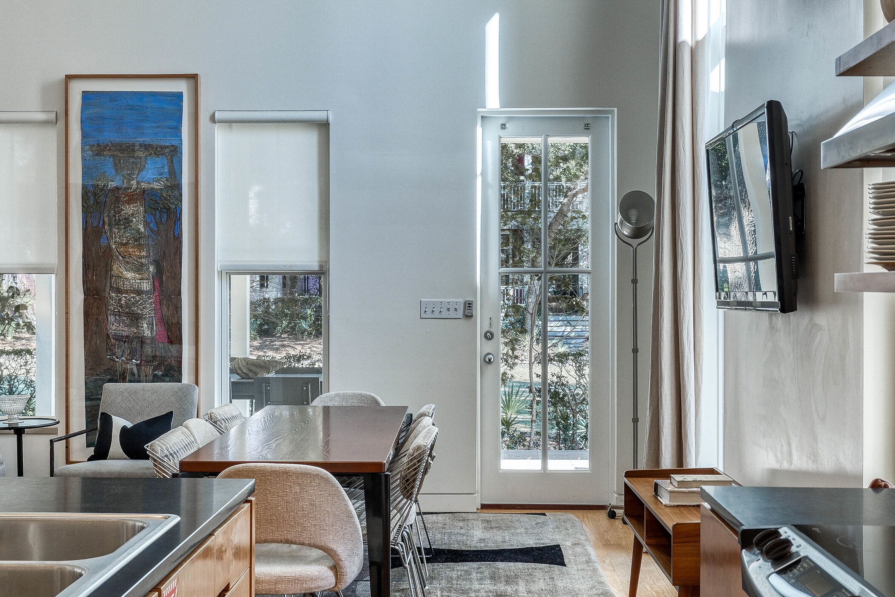 A modern kitchen with a dining area, large windows, and a view of the outdoors.