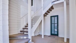 Eine Treppe, die zu einem zweiten Stockwerk mit weißer Fassade und einer grünen Tür führt.