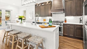 Una cocina moderna con una isla grande, armarios de madera oscura, electrodomésticos de acero inoxidable y encimera blanca.