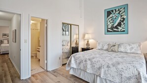 Ein Schlafzimmer mit Bett, Nachttischen, einem Spiegel und einem Bild an der Wand.