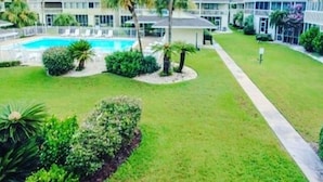 Ein Hotel mit Schwimmbad, Palmen und einem gepflegten Rasen.
