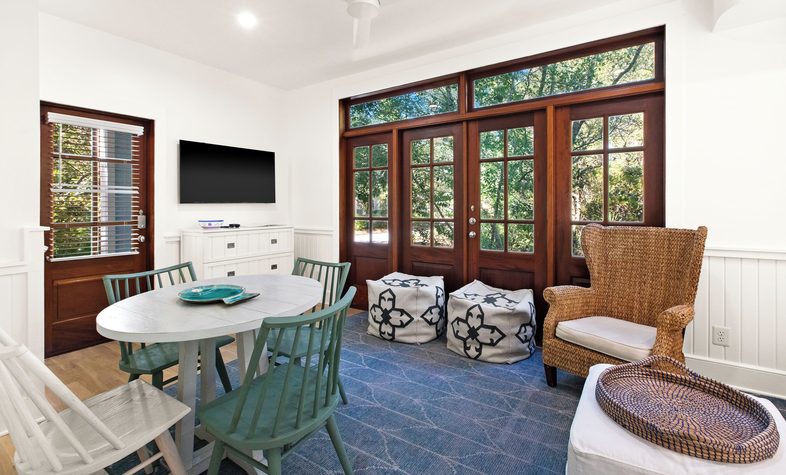 A dining area with a round table, chairs, and a television mounted on the wall.