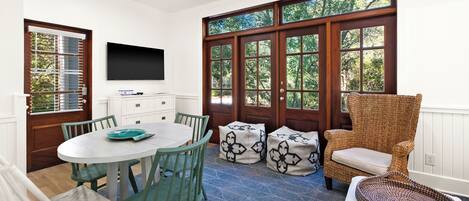 A dining area with a round table, chairs, and a television mounted on the wall.