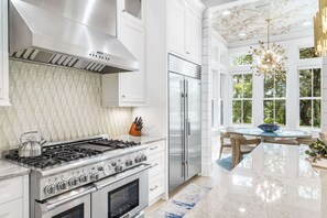 A modern kitchen with stainless steel appliances, a large island, and a dining area with a chandelier.