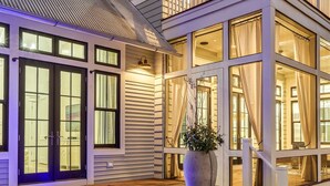 A pool area with a wooden deck, a large planter with plants, and a view of the interior through large windows. - Amenity Loaded Designer Home on Western Lake with Pool, Elevator, Bikes, LSV (Santa Rosa Beach)