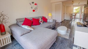 A modern living room with a grey sofa, red and white cushions, a small round table, and a lamp. - JUNGLE LUXURY FLAT WITH BALCONY AND PRIVATE PARKING IN CASSIS CENTER+WIFI (Cassis)