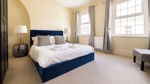 A bedroom with a large bed, two bedside lamps, a round side table, and a bench. - Salisbury Residences by Charles Hope (Salisbury)