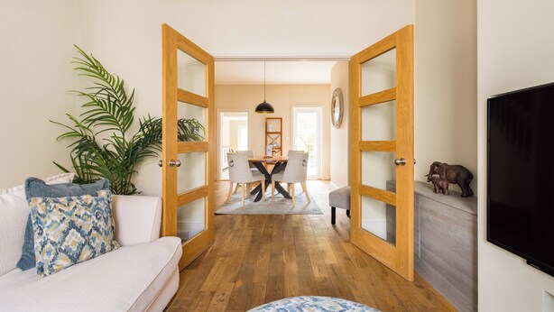 A living room with a sofa, a coffee table, and a TV. There is a dining area with a table and chairs in the background. - Salisbury Residences by Charles Hope (Salisbury)
