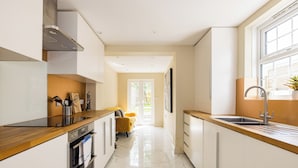 A modern kitchen with white cabinets, a wooden countertop, and a stainless steel sink. - Salisbury Residences by Charles Hope (Salisbury)