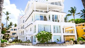 A multi-story hotel with balconies, large windows, and a pool area. - Stunning Ocean View Condo in Punta Cana (Punta Cana)