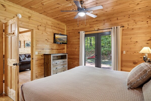 A wooden cabin bedroom with a bed, a ceiling fan, a dresser, and a television. - Kozy Bear 3 King BRs | Hot Tub | Pool Table (Sevierville)