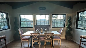 A dining area with a wooden table and chairs, large windows with a view of trees, and a sign that reads "EXPLORE".
