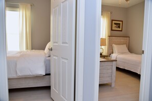 A hotel room with two beds, a wooden nightstand, and a framed picture on the wall.