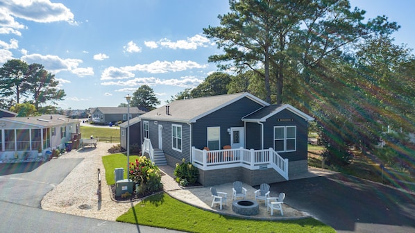 A single-story house with a porch, a small deck, and a fire pit area.