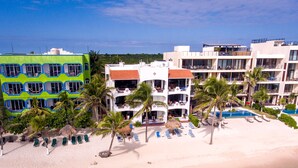 Ein Strandhotel mit mehreren Balkonen, einem Pool und Palmen.