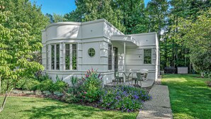 A modern, white, two-story house with a curved facade, surrounded by lush greenery and a well-maintained lawn. - Sleepy Hollow Beach Resort, Cottage 9 – Family Fun on Lake Michigan! (South Haven)