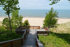 Une promenade en bois qui mène à une plage de sable et offre une vue sur l’océan.