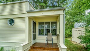 A single-story house with a front porch, a set of wooden steps leading to the entrance, and a chair placed on the porch.
