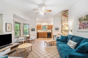 Un espacio habitable compacto con kitchenette, comedor y zona de estar con sofá azul.