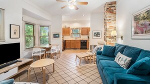 Un espacio habitable compacto con kitchenette, comedor y zona de estar con sofá azul.