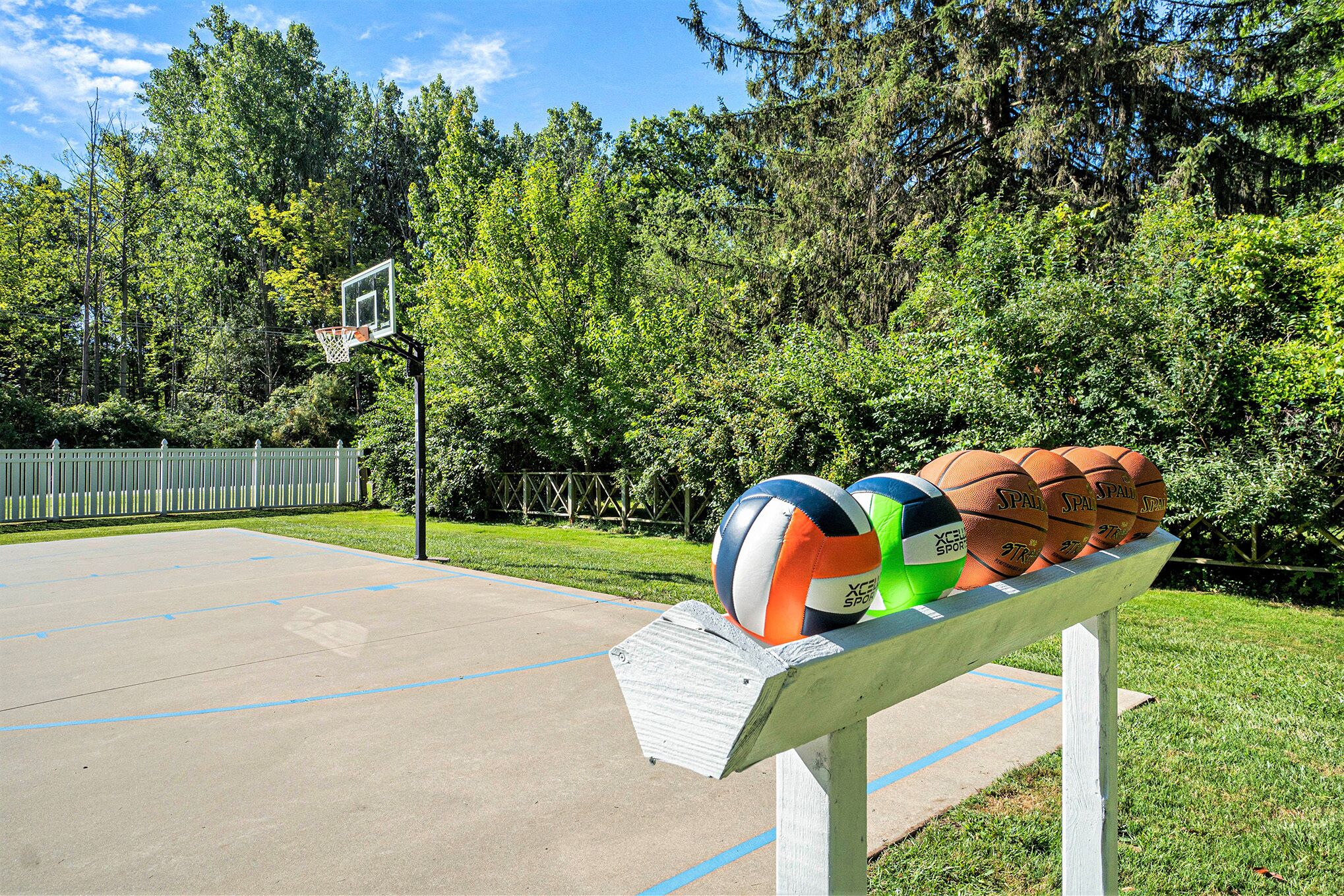A basketball court with a bench holding volleyballs and basketballs.