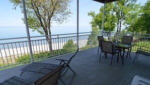 Un espacio al aire libre cubierto con vista al mar, que incluye una mesa, sillas y una barandilla.