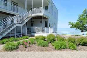 A two-story building with a white exterior, a balcony on the upper floor, and a staircase leading to the entrance.
