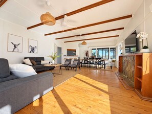 A spacious living area with a sofa, chairs, a dining table, and a kitchen in the background.