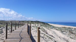 Pasarela de madera que conduce a una playa bajo un cielo despejado.