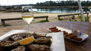 Una mesa con una fuente de ostras, una copa de vino blanco y rebanadas de pan con mantequilla y mermelada.
