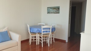Ein Essbereich mit Tisch und Stühlen, eine Couch mit Kissen und einem Bild an der Wand.