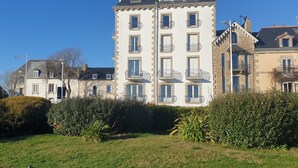 Ein mehrstöckiges Gebäude mit Balkonen, einem gepflegten Rasen und blauem Himmel.