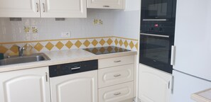 A kitchen with white cabinets, a dishwasher, a sink, and an oven.