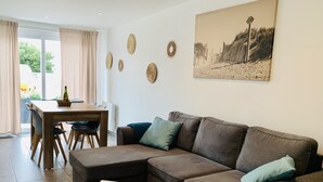 A modern living room with a brown leather sofa, a white coffee table, and a dining area with a wooden table and chairs. - Villa du Pêcheur, Gâvres Peninsula (Gâvres)