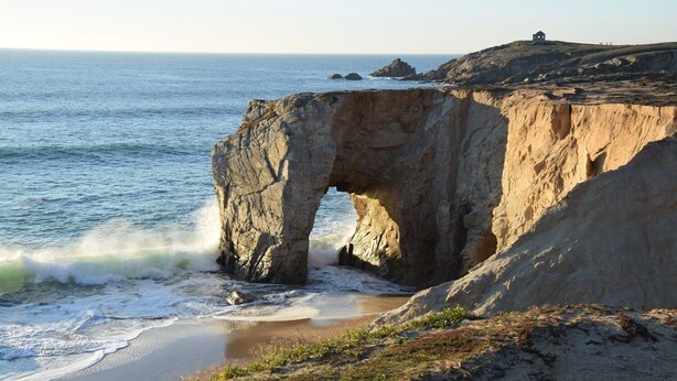 A coastal landscape with a prominent rock formation featuring a natural arch. - Villa du Pêcheur, Gâvres Peninsula (Gâvres)