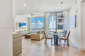 Enjoy a city view from the large window in this stylish living space, featuring a dining table and comfortable seating area.