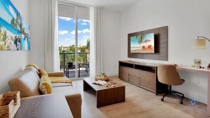 Un soggiorno moderno con divano, tavolino, televisione e un balcone con vista.