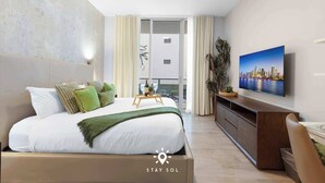 A modern hotel room with a large bed, a TV, and a balcony with curtains.