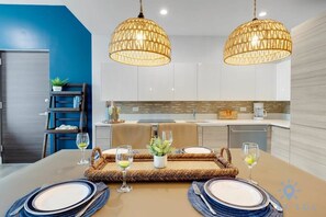 Enjoy meals in this stylish kitchen and dining area, featuring a large table for four and ample lighting.