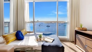 Ein Hotelzimmer mit großem Fenster und Blick auf Boote auf dem Wasser.