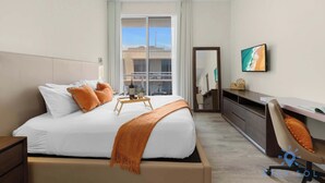A hotel room with a bed, a desk, a chair, a TV, and a window with a view of buildings. - Hot tub & Unique Rooftop|Hollywood Broad–walk (Hollywood)