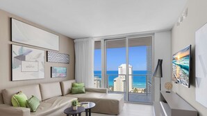 A modern living room with a large window offering a view of the ocean and cityscape. - Breathtaking Front Ocean View: Amazing Pools (Hollywood)
