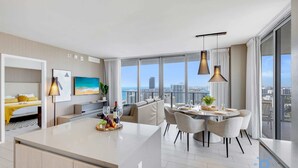 Un appartement moderne doté d’un grand îlot central dans la cuisine, d’un coin repas et d’un balcon offrant une vue sur la ville.