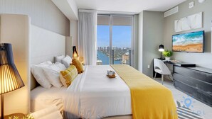 Une chambre d’hôtel avec un grand lit, un bureau, une chaise, une télévision et une vue sur la ville.