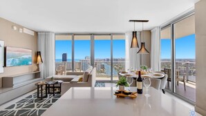 A modern living room with a large window, a dining area, and a sofa. - Luxury w/ stunning view |Balcony |Amazing Pools (Hollywood)