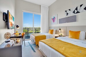 A hotel room with two beds, a desk, a TV, and artwork on the walls. - Luxury Amenities: Infinity Pool+ Gym+ Hot Tub (Hollywood)